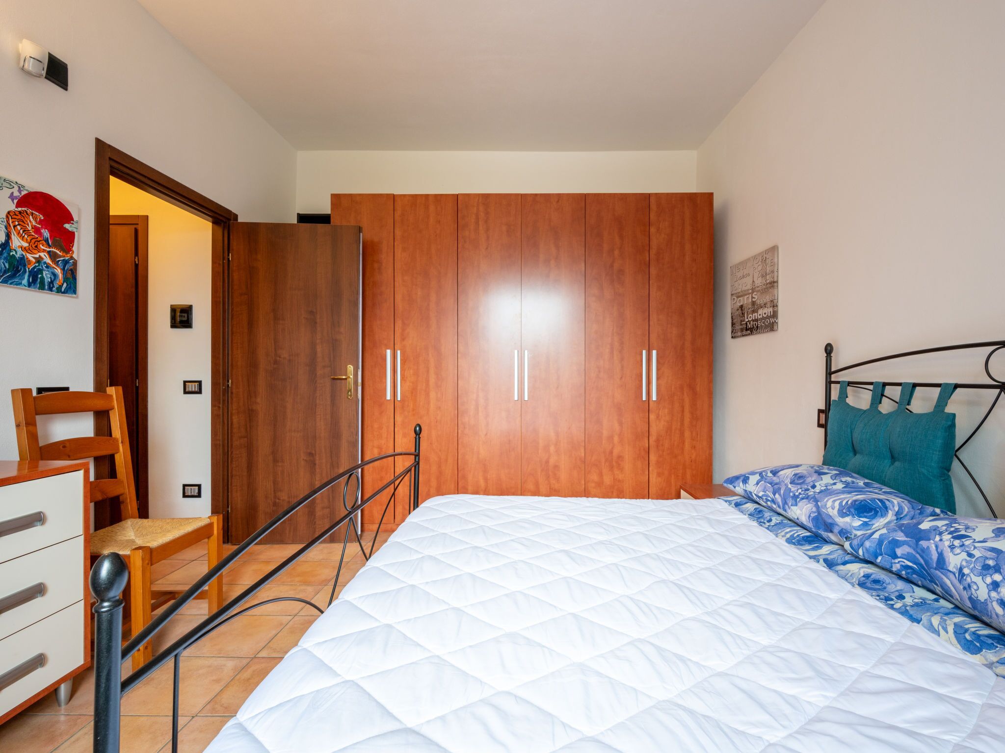 Una camera da letto con un letto, un armadio, una sedia e un tavolino.