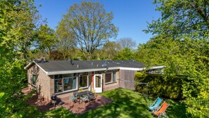 A modern house with a patio, a barbecue, and a lawn.