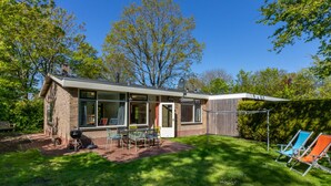 A modern house with a patio, a barbecue grill, and a small deck.