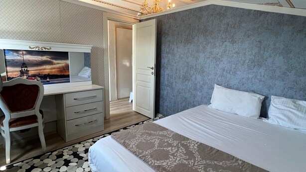 A bedroom with a bed, a desk, and a chair. There is a door leading to another room. - Mihri Hatun Suit Otel (Istanbul)