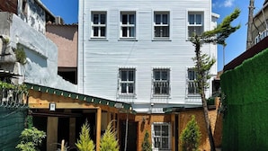 A two-story building with a sign reading "Mihri Hatun Suit Otel". There are outdoor seating areas with tables and chairs, and potted plants around the building. - Mihri Hatun Suit Otel (Istanbul)