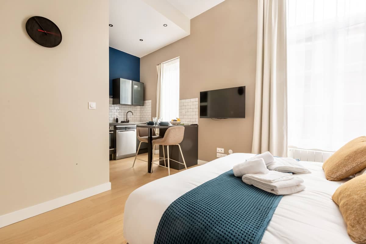 Una habitación de hotel moderna con cama, escritorio, kitchenette y televisor.