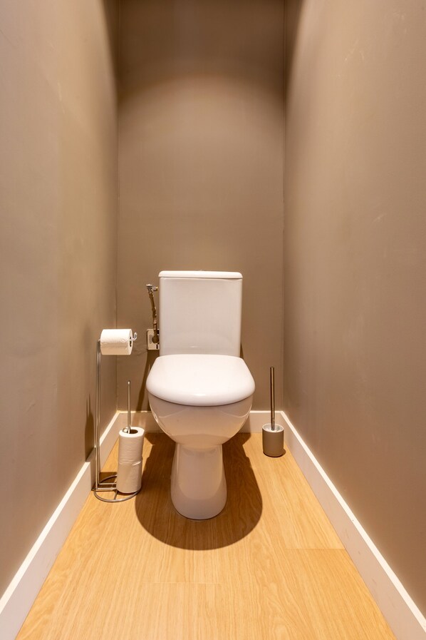 A modern bathroom with a white toilet, a toilet paper holder, and a bidet. - Au Chat Qui Dort Lille - Gare (Lille)