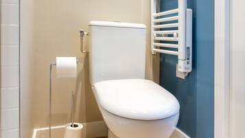 Um banheiro moderno com vaso sanitário branco, porta-papel higiênico e porta-toalhas.