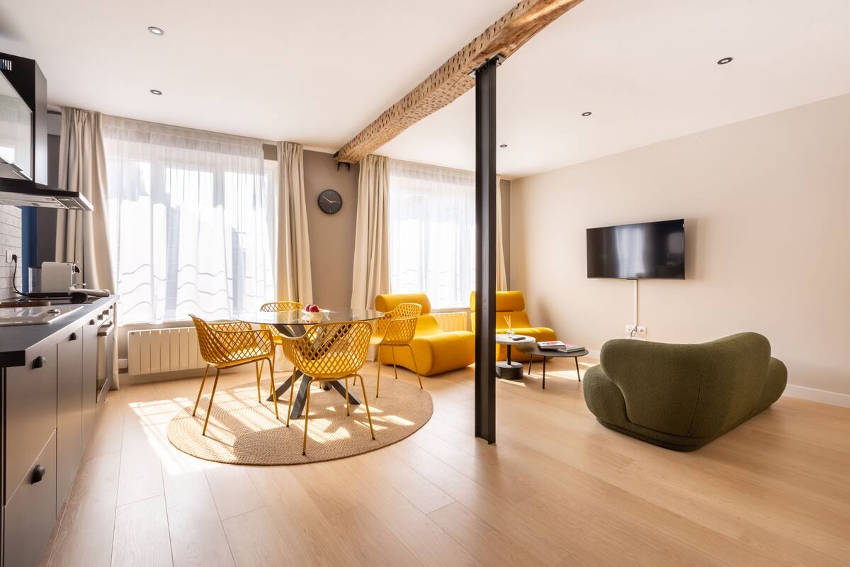 Una sala de estar moderna con comedor, un sofá, un televisor y una cocina.