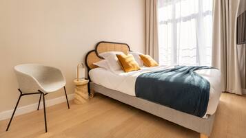 A modern bedroom with a bed, a chair, and a bedside table.