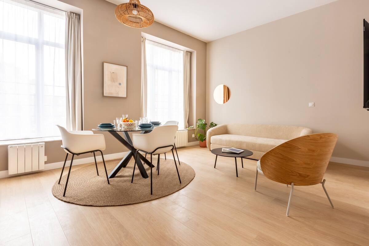 Una sala de estar moderna con zona de comedor, que incluye una mesa redonda, sillas, un sofá y una mesa de centro.