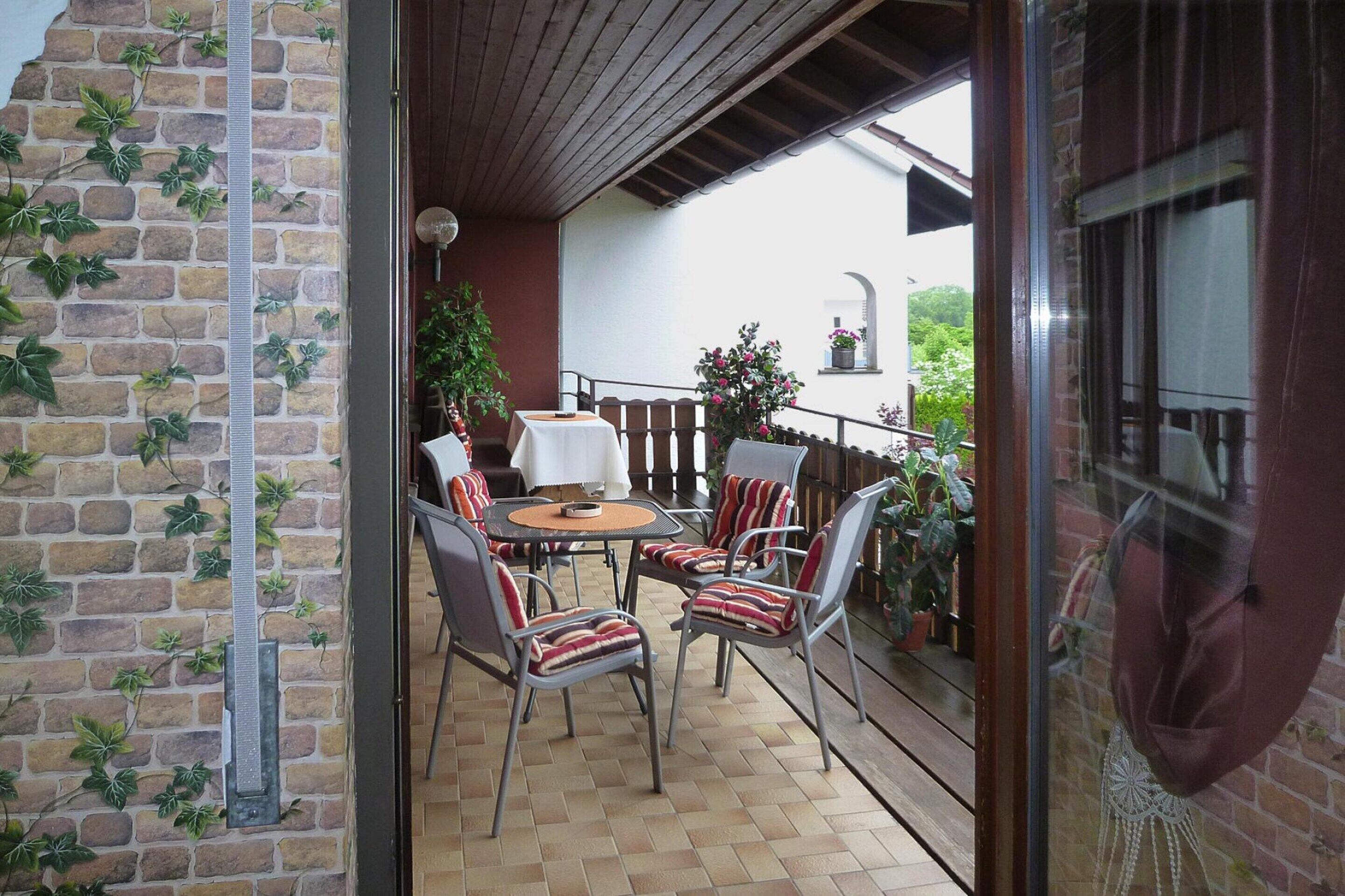 An outdoor patio with a brick wall, a wooden ceiling, and a table with chairs.