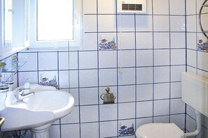 A bathroom with a sink, toilet, and a window.