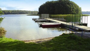 A calm lake with a dock extending into the water, surrounded by greenery and a forested hill. - Twin Bungalow at Black Lake, Schwarz (Schwarz)