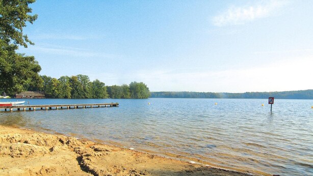 A sandy beach with a dock extending into calm water, surrounded by trees. - Twin Bungalow at Black Lake, Schwarz (Schwarz)