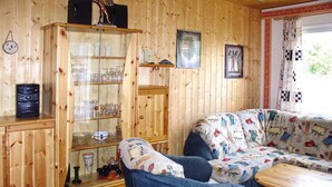 A wooden interior with a glass-fronted cabinet, a patterned sofa, and a small wooden table. - Twin Bungalow at Black Lake, Schwarz (Schwarz)