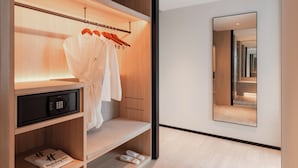 A modern hotel room with a walk-in closet, a microwave, a shelf with slippers, and a mirror reflecting the room. - Holiday Inn Kuala Lumpur Bangsar (Kuala Lumpur)