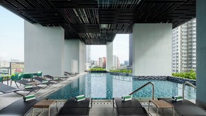 A rooftop swimming pool with lounge chairs and a view of the cityscape. - Holiday Inn Kuala Lumpur Bangsar (Kuala Lumpur)