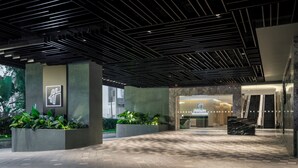A modern hotel entrance with a geometric ceiling design, a reception desk, and potted plants. - Holiday Inn Kuala Lumpur Bangsar (Kuala Lumpur)