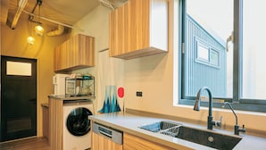 Une cuisine moderne avec des meubles en bois, un lave-linge encastré, un évier et des luminaires suspendus.