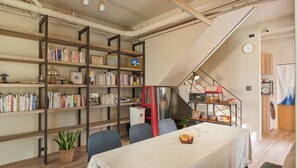 Une pièce chaleureuse comprenant une table à manger, des chaises, une bibliothèque et un escalier.