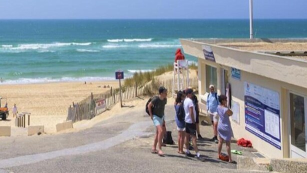 A beachside location with a flagpole, a lifeguard tower, and a building with informational signs. - Ferienhaus im Hafendorf Vieregge (Neuenkirchen)