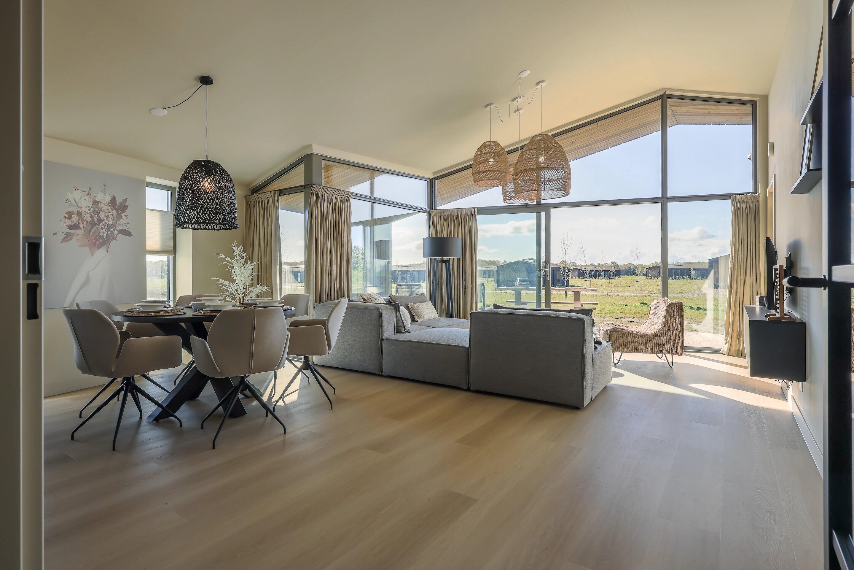 Een ruime woonkamer met een groot raam, een eettafel met stoelen en een moderne bank.
