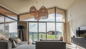 Een moderne woonkamer met een modulaire bank, grote ramen en een flatscreentelevisie.