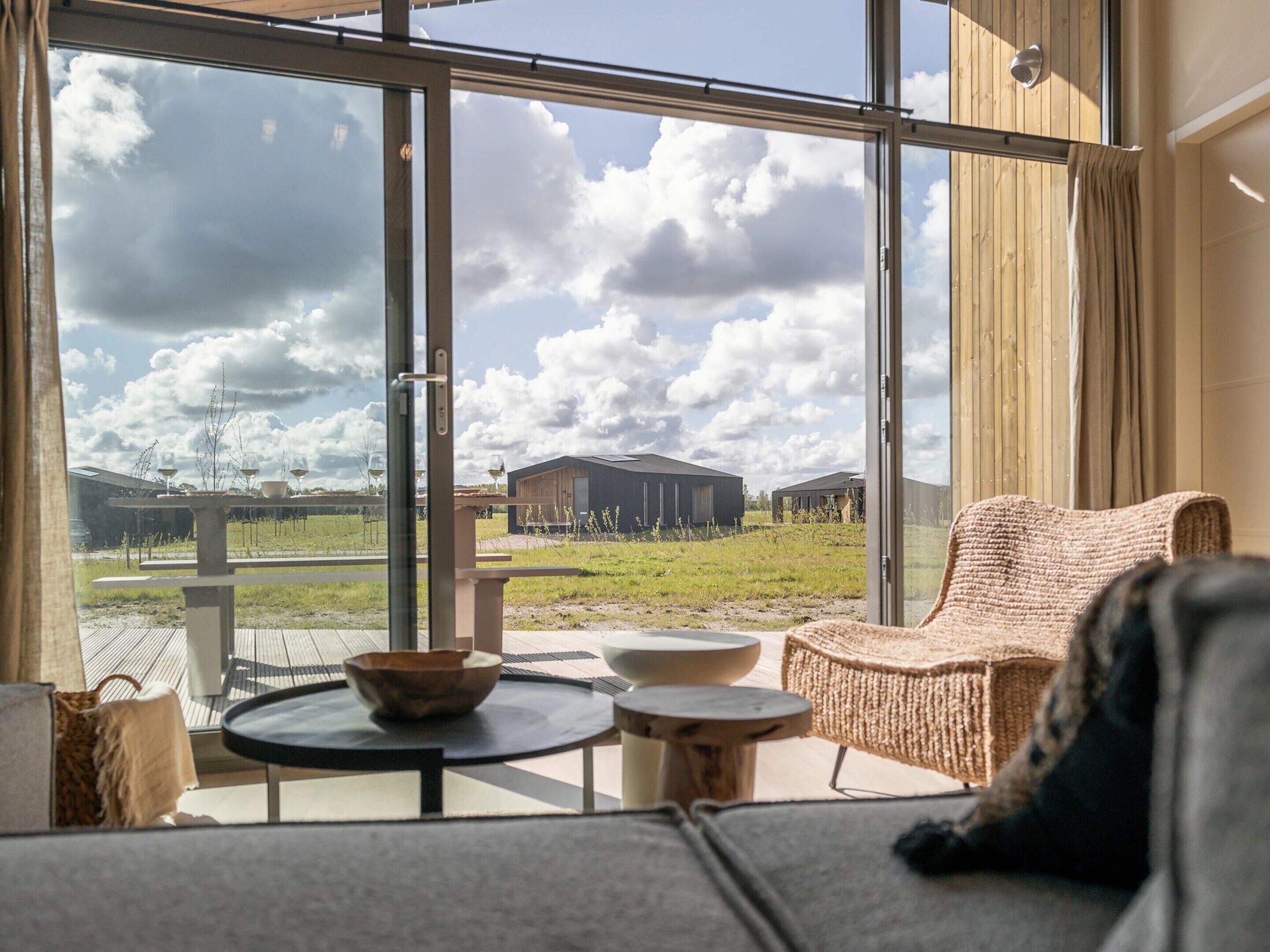 A modern interior with a large window offering a view of a rural landscape and a wooden building.