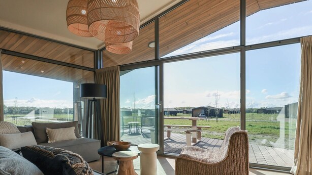 Een modern interieur met grote ramen, een bank, een stoel en een tafel.