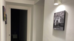 A hallway with a door leading to a dark room, a wall-mounted light fixture, and a framed picture on the wall. - A stone's throw from the historic Ballaró market and the historic center of Palermo (Palermo)