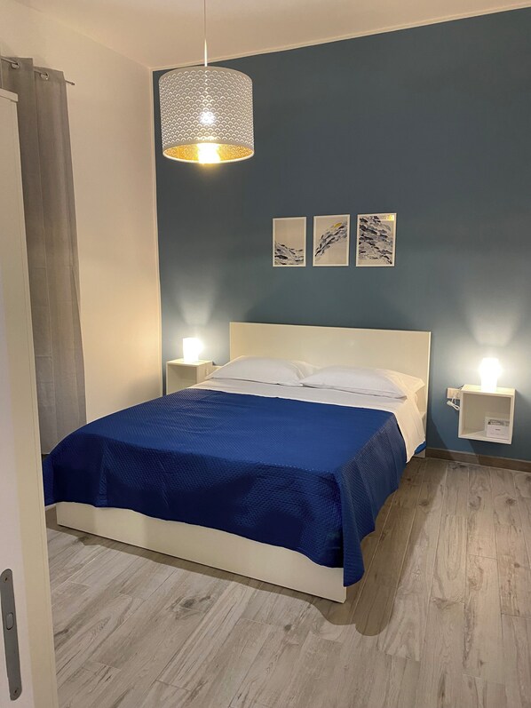 A neatly made bed with a blue bedspread, a white headboard, and two bedside lamps.