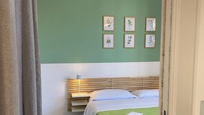 A bedroom with a green wall, a bed with a white and green bedspread, a wooden headboard, and four framed botanical prints. - A stone's throw from the historic Ballaró market and the historic center of Palermo (Palermo)