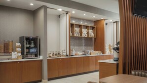 A modern cafe with wooden counters, a coffee machine, and a display of pastries. - SpringHill Suites by Marriott Lexington Frankfort (Frankfort)