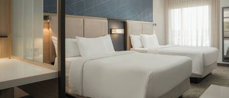 Habitación de hotel con dos camas, diseño moderno, un ventanal grande con cortinas y un patrón geométrico en la pared.