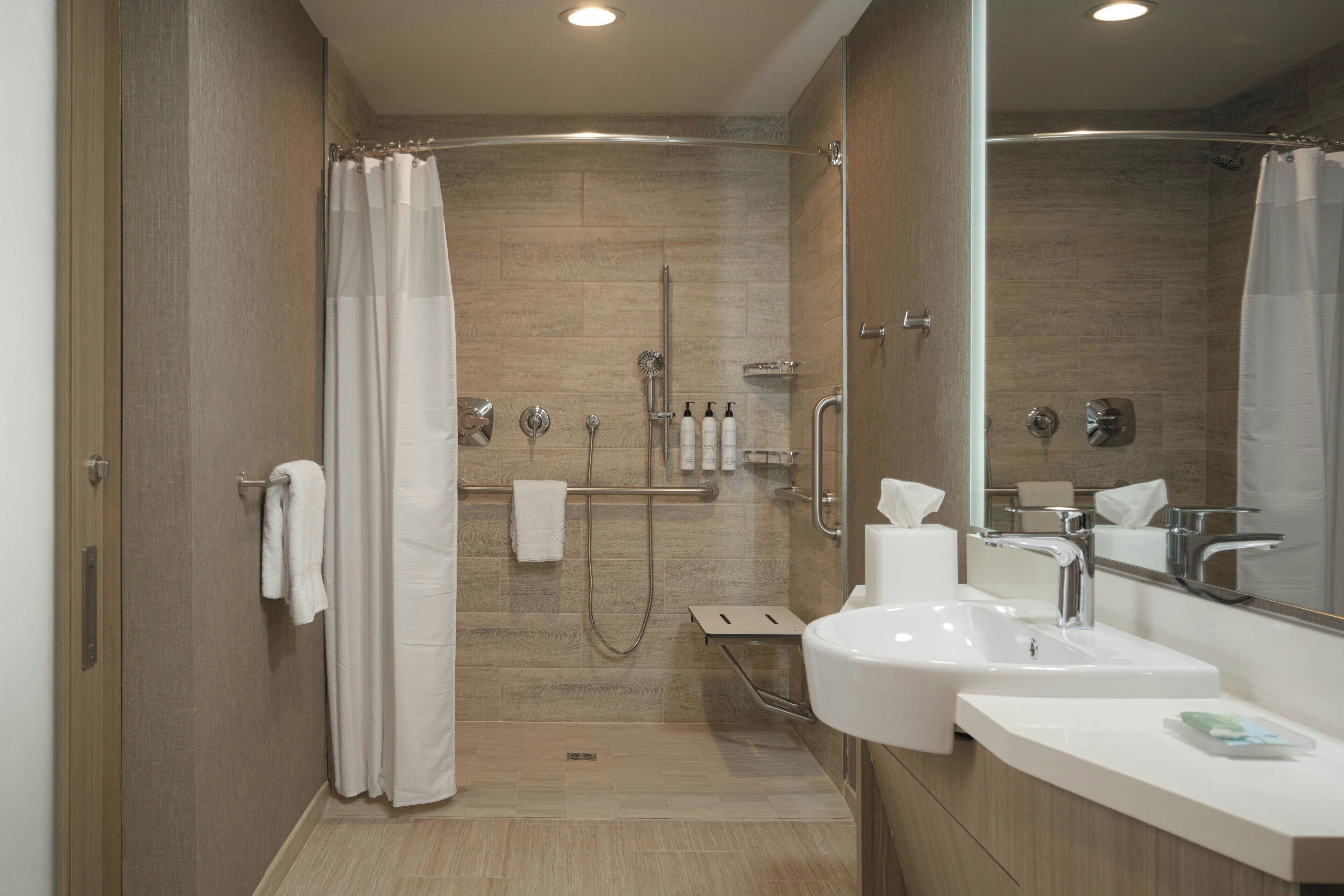 A modern bathroom with a shower, a sink, and a mirror.