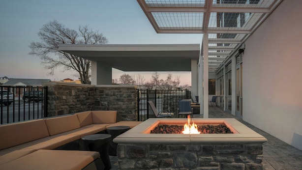 An outdoor seating area with a stone fire pit and a covered patio. - SpringHill Suites by Marriott Lexington Frankfort (Frankfort)
