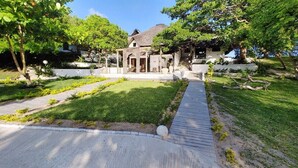 Una casa moderna con jardín cuidado, entrada pavimentada y terraza de madera.