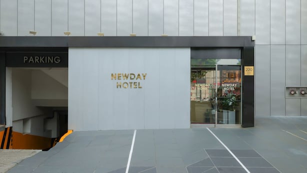 L’extérieur de l’hôtel Newday, avec une entrée bien visible et un espace de stationnement.