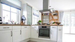 Una cocina moderna con armarios blancos, horno empotrado y una ventana con persianas.