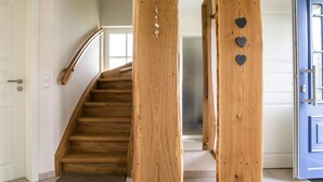 Una escalera de madera con barandilla, una puerta azul y una pared decorada con corazones.