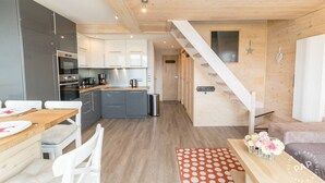 A modern kitchen with grey cabinets, a wooden dining table, and a staircase leading to another level.