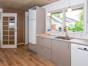 A modern kitchen with a built-in Bosch dishwasher, a wooden floor, and a window with a view of a garden. - 4 Star Holiday Home in Thyholm (Thyholm)