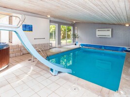 Una piscina con un tobogán azul, un jacuzzi y vistas al exterior.