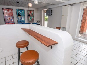 A pool area with a white wall, a wooden bar, and two brown stools. - 4 Star Holiday Home in Thyholm (Thyholm)