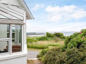 A coastal property with a view of the sea, a grassy area, and a white building with large windows. - 4 Star Holiday Home in Thyholm (Thyholm)