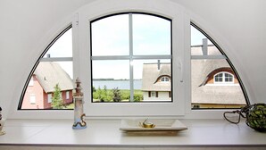 Una habitación con un amplio ventanal de arco que da a un cuerpo de agua y edificios.