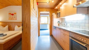 A compact kitchen with wooden cabinetry, a built-in oven, and a window providing natural light. - Spacious Apartment With Solarium (Gaschurn)