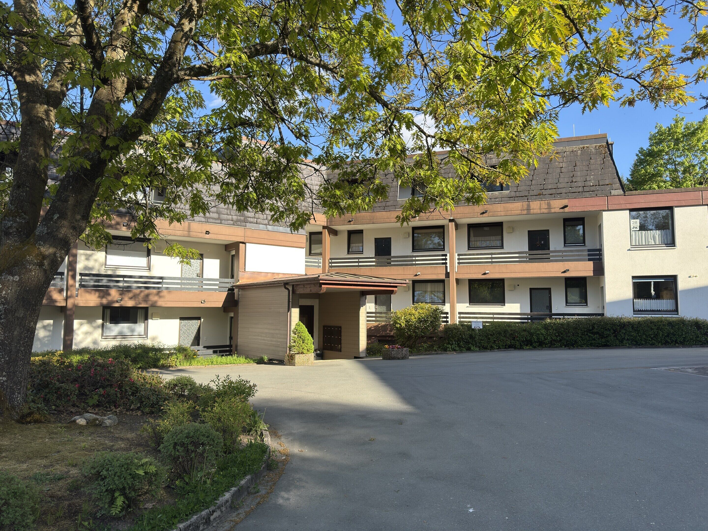 A multi-story building with a flat roof, large windows, and a parking lot in front.