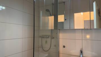 A modern bathroom with a glass-enclosed shower, a sink, and a mirror.