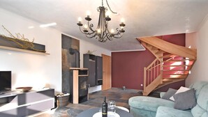 A modern living room with a fireplace, a staircase, and a flat-screen TV. - Ferienwohnung Nahe Wernigerode (Wernigerode)