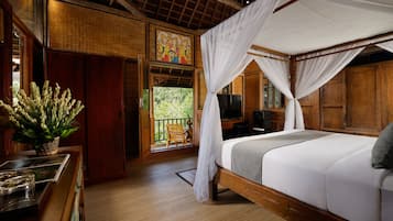 Una habitación con cama, televisión y balcón con vistas al verdor.