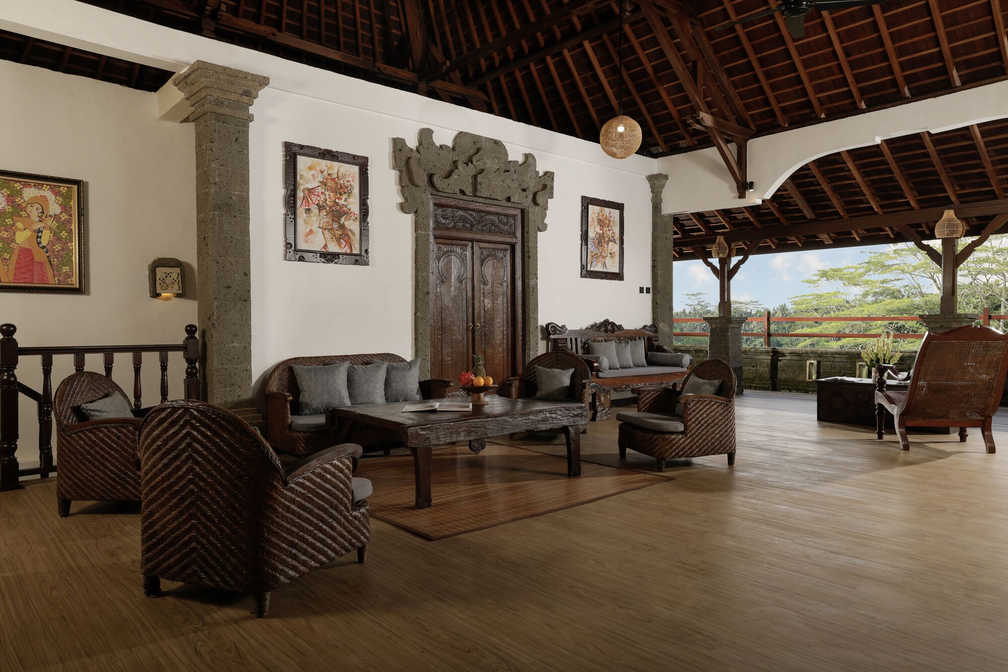 A spacious lounge area with wooden furniture, a stone wall, and artwork on the walls.