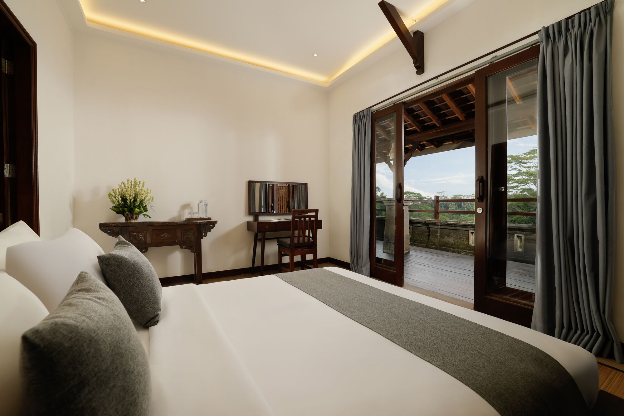 Une chambre avec un grand lit, un bureau et une vue sur un balcon.